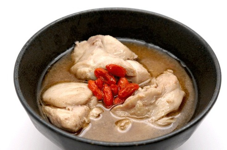 A black bowl of sesame oil chicken soup with goji berries — a classic Zuo Yue Zi postpartum dish from JingMommy